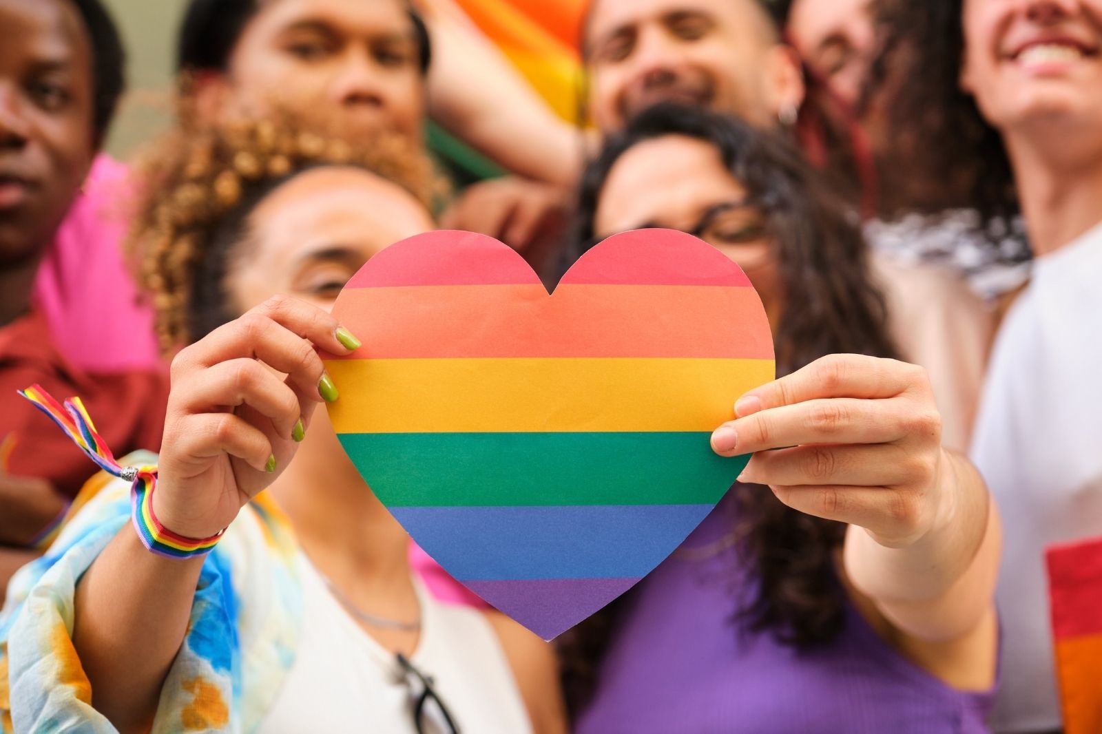 Diverse hands holding a rainbow botanical arrangement